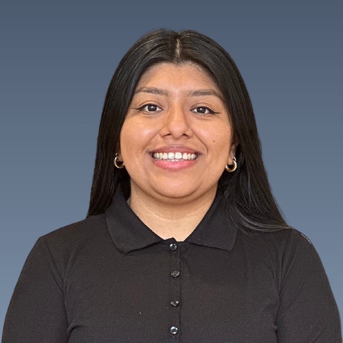 Smiling woman with long dark hair wearing black polo shirt against gray background.
